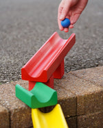 with a hand rolling some wooden balls down it