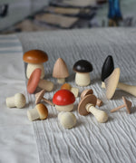 The wooden mushrooms from the Erzi Forest mushrooms in a box set placed on a striped tablecloth.
