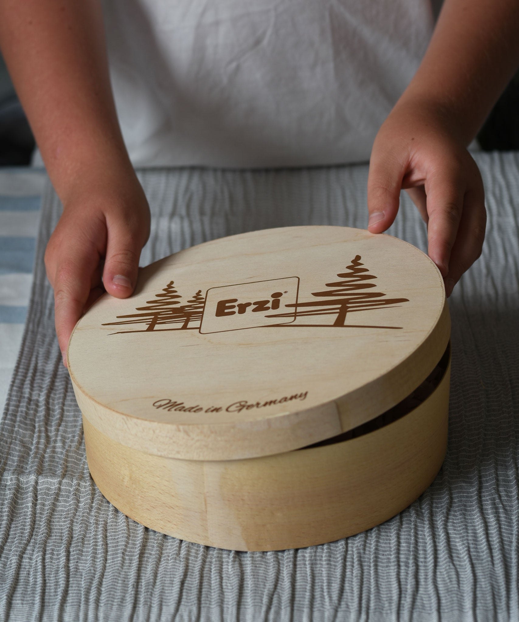Erzi wooden painted forest toy mushrooms in a round wooden box. A child can be seen lifting the lid off the box.
