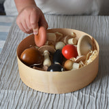 A child picking up a pink coloured mushroom from the Erzi Forest mushrooms in a box set out of the box.