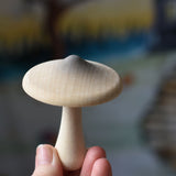 A white coloured mushroom with grey shading on the top from the Erzi Forest mushrooms in a box set held up in an adult's hand.