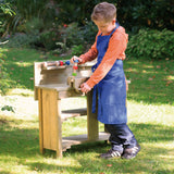 A child pretending to build things with the Erzi wooden toy workbench, outside on a sunny day.