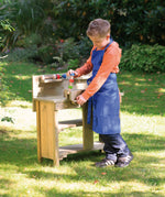 A child pretending to build things with the Erzi wooden toy workbench, outside on a sunny day.