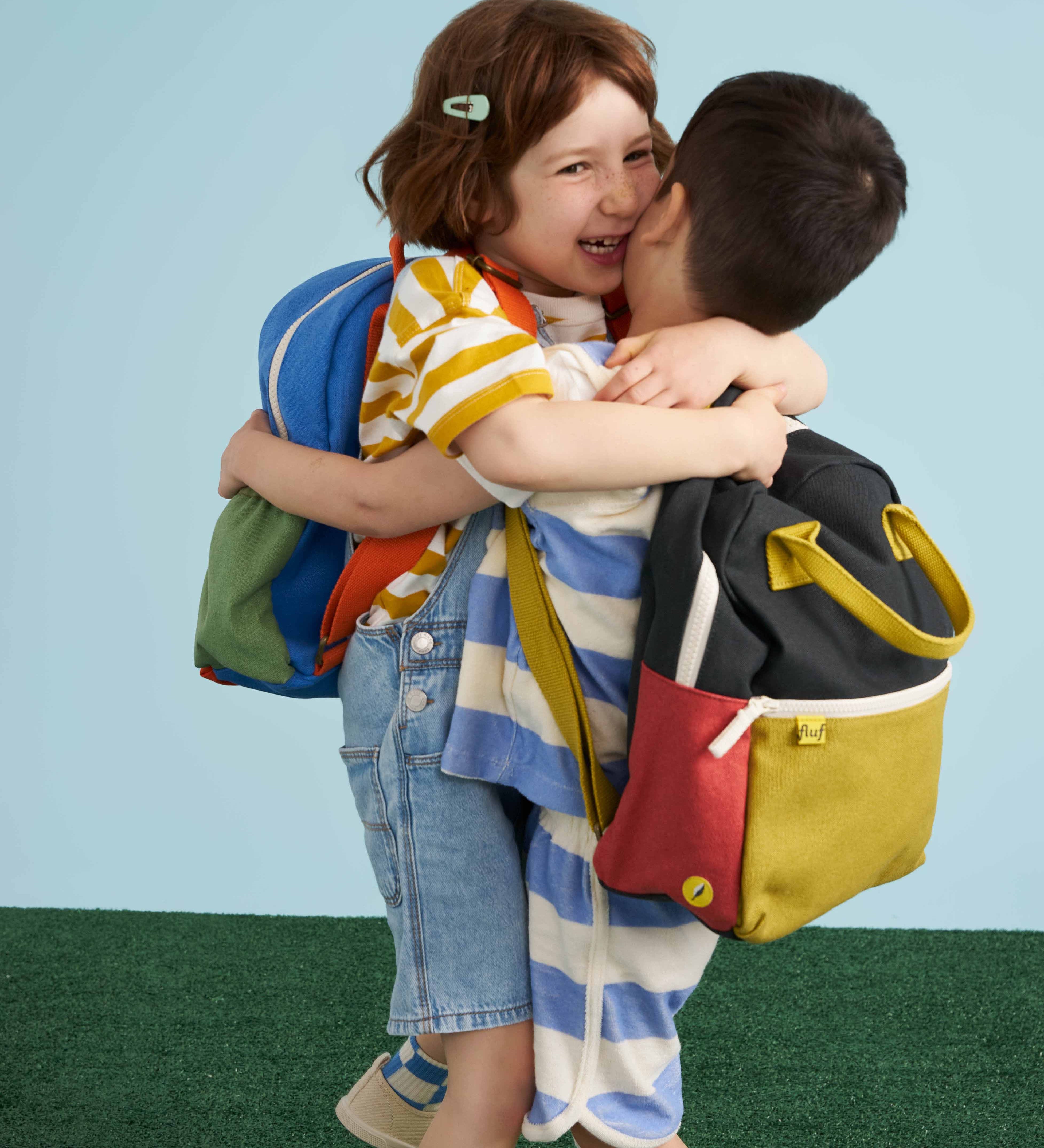Two children each wearing a Fluf junior organic cotton backpack.