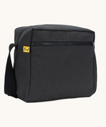 A side angle view of the black carbon coloured Fluf Crossbody Bag. The bag has a black coloured zip and crossbody strap.