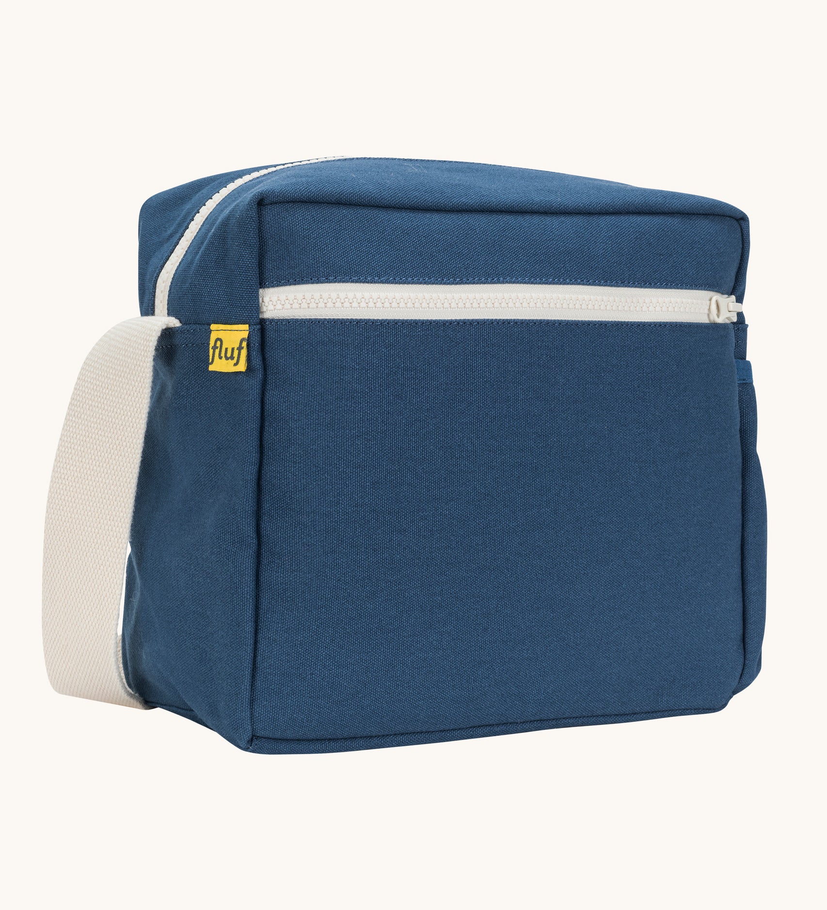 A side angle view of the classic navy coloured Fluf Crossbody Bag. The bag has and off white coloured zip an crossbody strap.