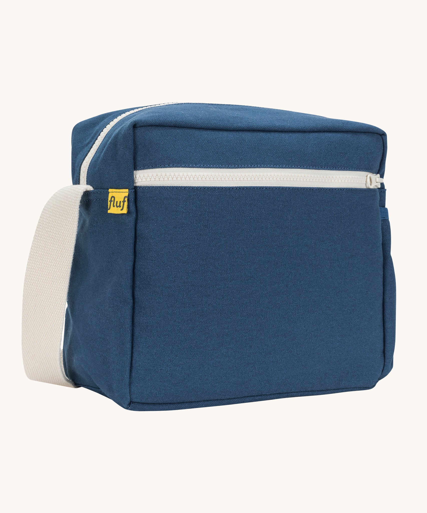 A side angle view of the classic navy coloured Fluf Crossbody Bag. The bag has and off white coloured zip an crossbody strap.