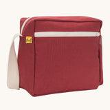 A side angle view of the vintage burgundy coloured Fluf Crossbody Bag. The bag has and off white coloured zip an crossbody strap.