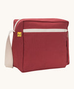 A side angle view of the vintage burgundy coloured Fluf Crossbody Bag. The bag has and off white coloured zip an crossbody strap.