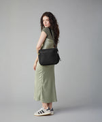 A woman carrying the adjustable strap organic cotton crossbody lunch bag from Fluf in black