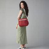 A woman in a green dress modelling the Fluf organic cotton crossbody lunch and every day bag in vintage burgundy