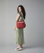 A woman in a green dress modelling the Fluf organic cotton crossbody lunch and every day bag in vintage burgundy