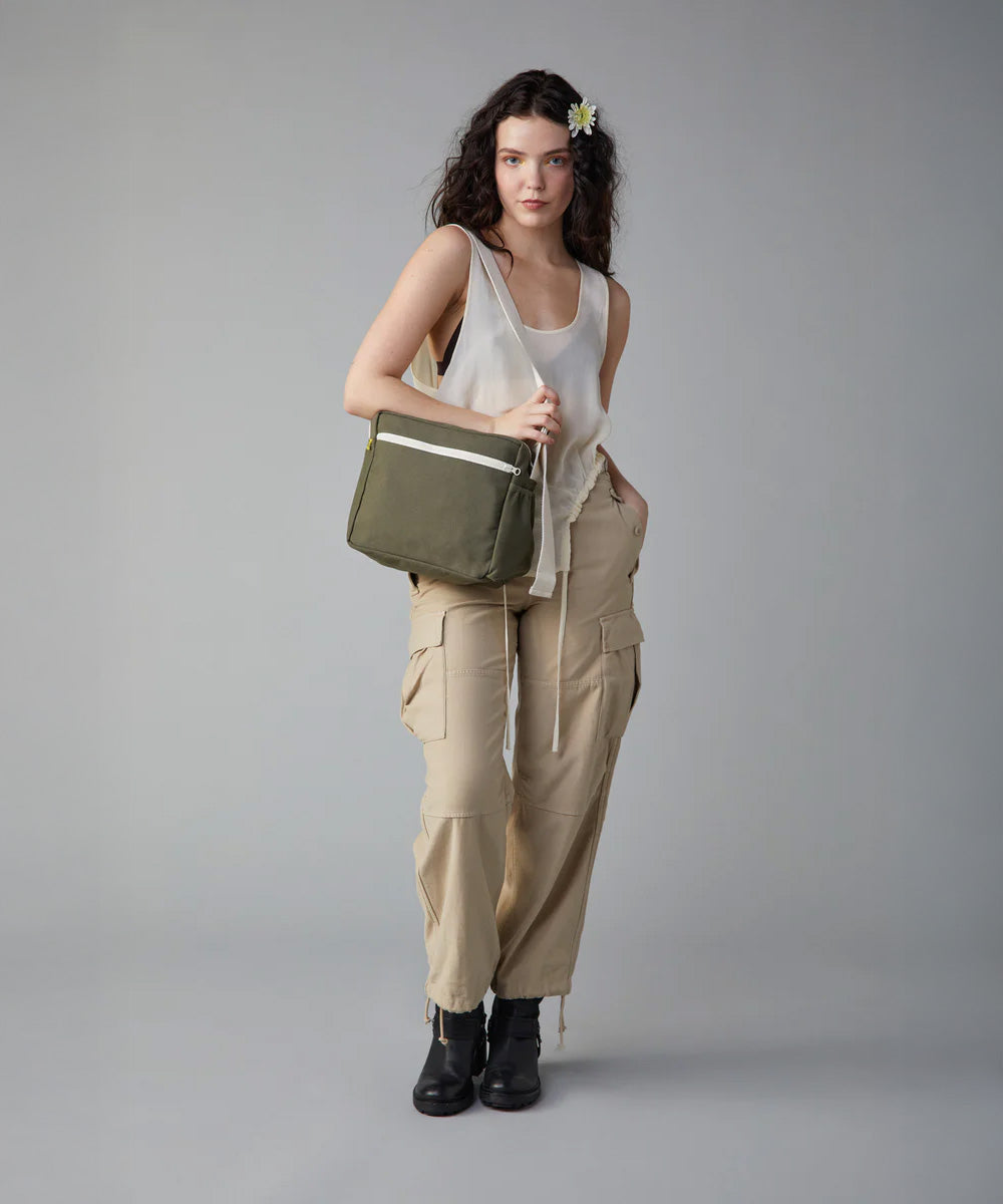 A woman modelling the Fluf organic cotton crossbody everyday lunch bag in olive green