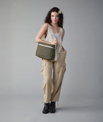 A woman modelling the Fluf organic cotton crossbody everyday lunch bag in olive green