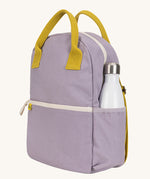 The organic cotton kids Fluf B-Pack Jr in lavender purple, the backpack is zipped up and there's a reusable water bottle in the side pocket.