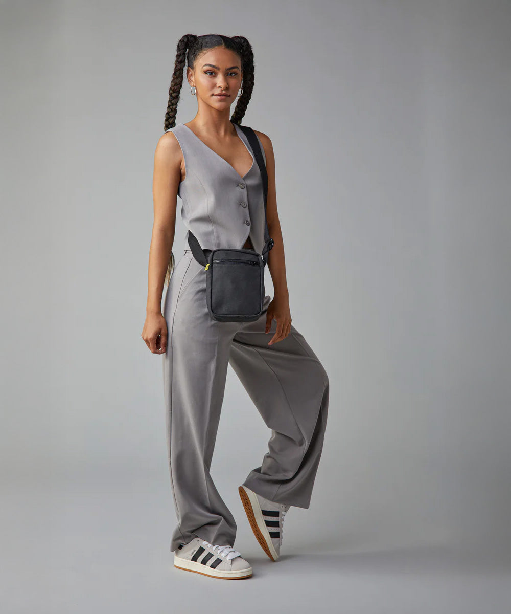 A woman in a trendy casual office wear suit, carrying the Fluf organic cotton mini crossbody bag in black