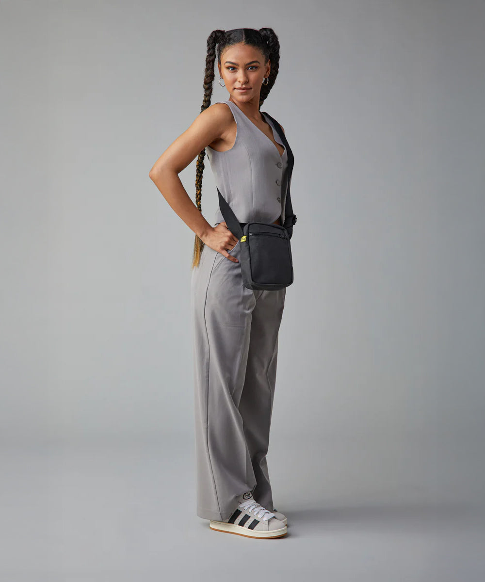 A woman in a trendy casual office wear suit, carrying the Fluf organic cotton mini crossbody bag in black