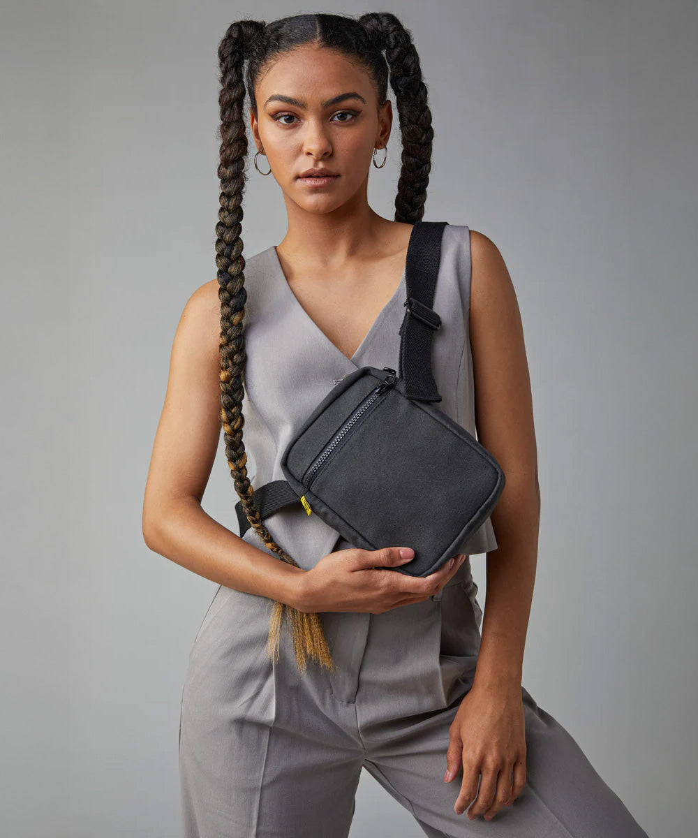A woman in a trendy casual office wear suit, carrying the Fluf organic cotton mini crossbody bag in black