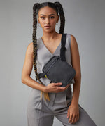 A woman in a trendy casual office wear suit, carrying the Fluf organic cotton mini crossbody bag in black