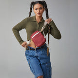 A woman with braided hair modelling the Fluf organic cotton mini crossbody bag, in vintage burgundy.