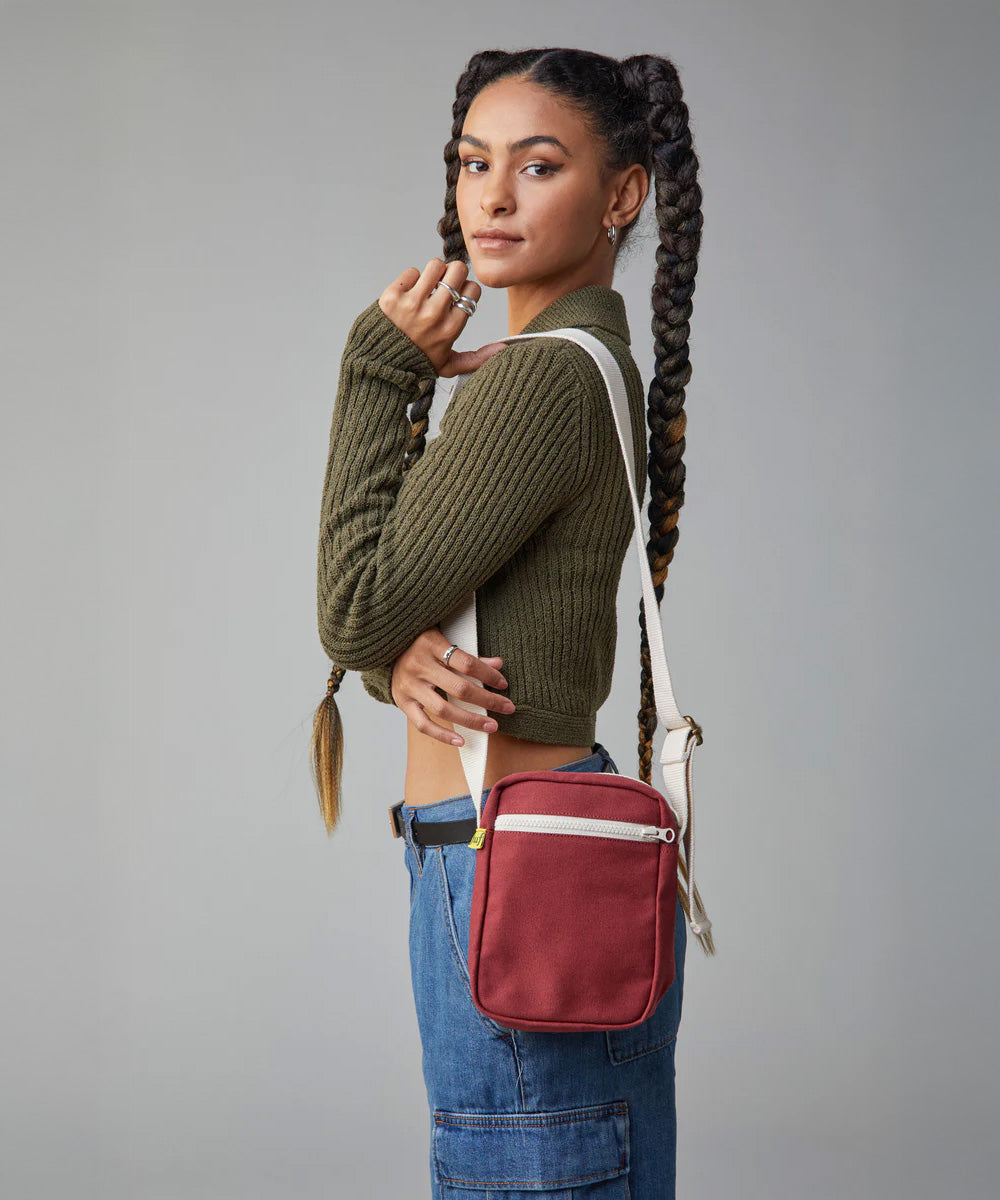 A woman modelling the Fluf organic cotton snack mini crossbody bag in burgundy, perfect for a festival bag