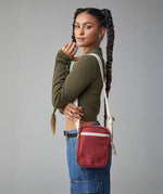 A woman modelling the Fluf organic cotton snack mini crossbody bag in burgundy, perfect for a festival bag