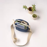 A top view of the Fluf organic cotton mini crossbody bag in navy, holding an iPhone and small notebook in the separated lined pockets.