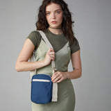 A woman in a green dress wearing the Fluf organic cotton mini crossbody travel organiser and snack bag in navy blue