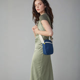 A woman in a green dress wearing the Fluf organic cotton mini crossbody travel organiser and snack bag in navy blue