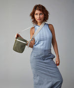A trendy woman holding the Fluf organic cotton , machine washable Mini Crossbody sports and travel bag  in olive green