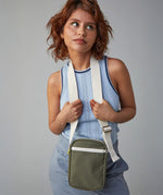 A woman with choppy ginger hair modelling the Fluf organic cotton mini crossbody ag in olive green