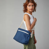 The side profile of a woman carrying the Fluf organic cotton crossbody lunch bag in navy blue over her shoulder.