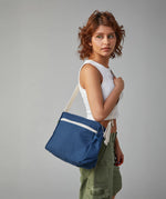 The side profile of a woman carrying the Fluf organic cotton crossbody lunch bag in navy blue over her shoulder.