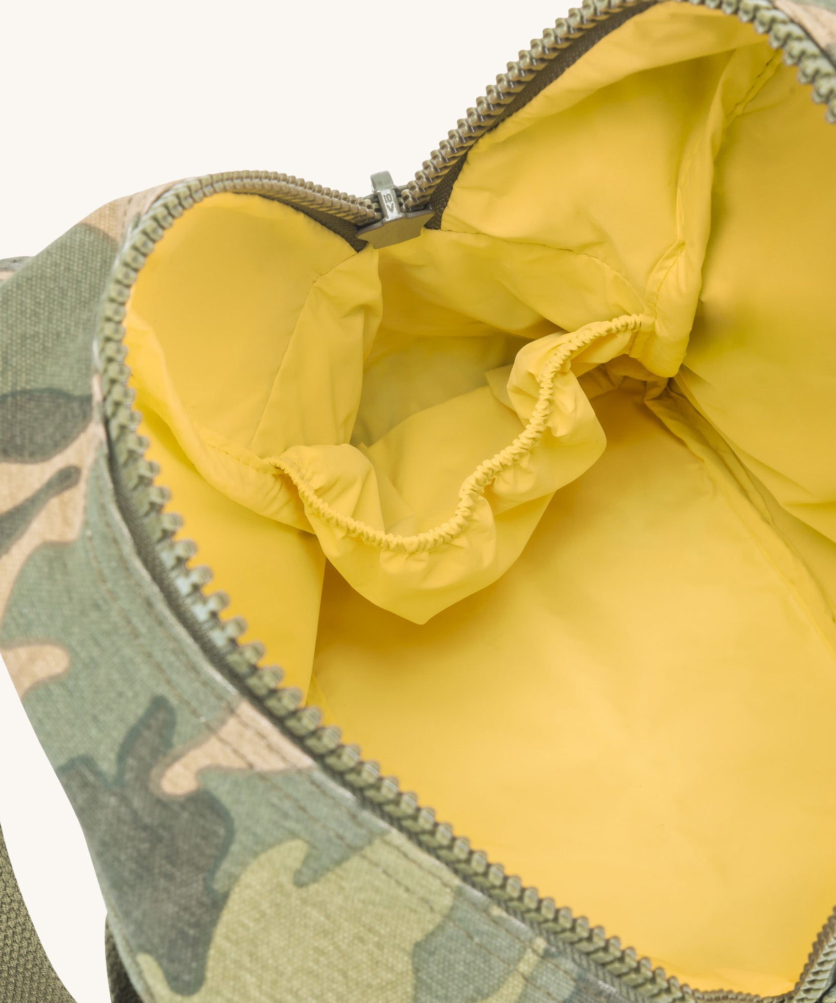 The yellow lined interior of the Fluf organic cotton zippered lunch bag, in a green camo print.