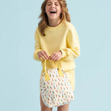 A young person laughing holding a Fluf organic cotton zippered lunch bag, featuring the ice cream cones print design.