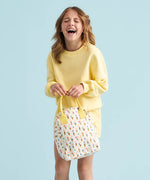 A young person laughing holding a Fluf organic cotton zippered lunch bag, featuring the ice cream cones print design.