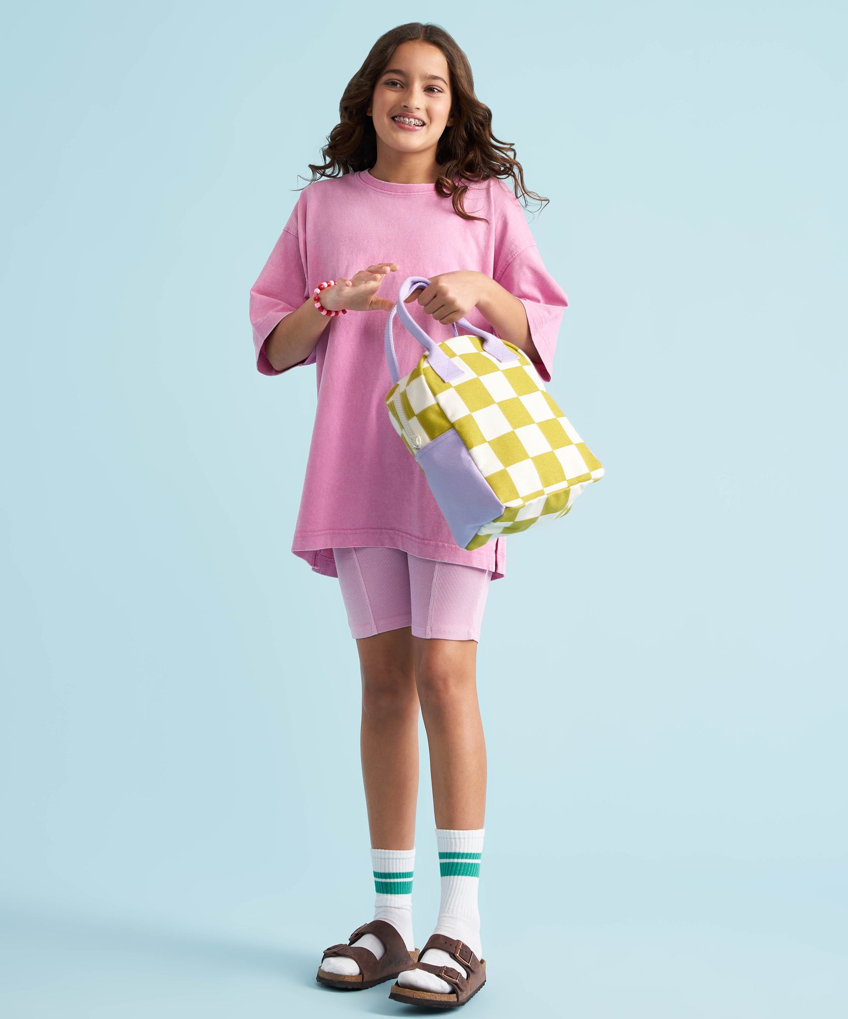 A young person holding Fluf organic cotton zippered lunch bag, featuring the checks pear design.