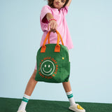 A young person holding a Fluf organic cotton zippered lunch bag, featuring the have a nice day design.