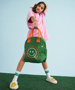 A young person holding a Fluf organic cotton zippered lunch bag, featuring the have a nice day design.
