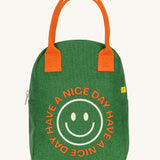 The Fluf organic cotton zippered lunch bag, featuring a emoji design with the words have a nice day on the front, orange handles and green side panels.