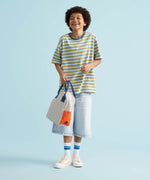 A child holding a Fluf organic cotton zippered lunch bag, featuring the nautical pencil stripe design.