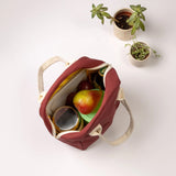 A top view of the Fluf organic cotton zippered lunch bag in a vintage burgundy colour, filled with food containers, fruit, and a water bottle.