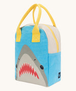 Fluf zip lunch bag in light blue and grey with a design of a shark's head on the bottom with a yellow handle and zip detail on a cream background.