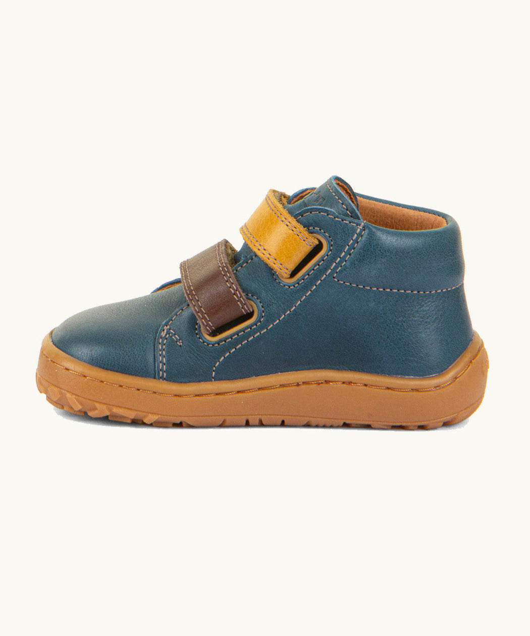 A side image of the Froddo barefoot first step baby shoe in dark denim available at Babipur showing the  2 velcro fastener in dark yellow and brown for a secure fit. Features a light brown grippy sole