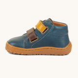 A side image of the Froddo barefoot first step baby shoe in dark denim available at Babipur showing the  2 velcro fastener in dark yellow and brown for a secure fit. Features a light brown grippy sole