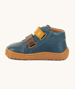 A side image of the Froddo barefoot first step baby shoe in dark denim available at Babipur showing the  2 velcro fastener in dark yellow and brown for a secure fit. Features a light brown grippy sole