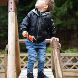 A child playing in the park and wearing the Froddo barefoot Tex Autumn children's shoe in dark blue available at Babipur. A children's waterproof shoe with a 2 velcro fastener on the front for a secure fit, padded ankle and a brown grippy sole.