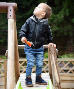 A child playing in the park and wearing the Froddo barefoot Tex Autumn children's shoe in dark blue available at Babipur. A children's waterproof shoe with a 2 velcro fastener on the front for a secure fit, padded ankle and a brown grippy sole.