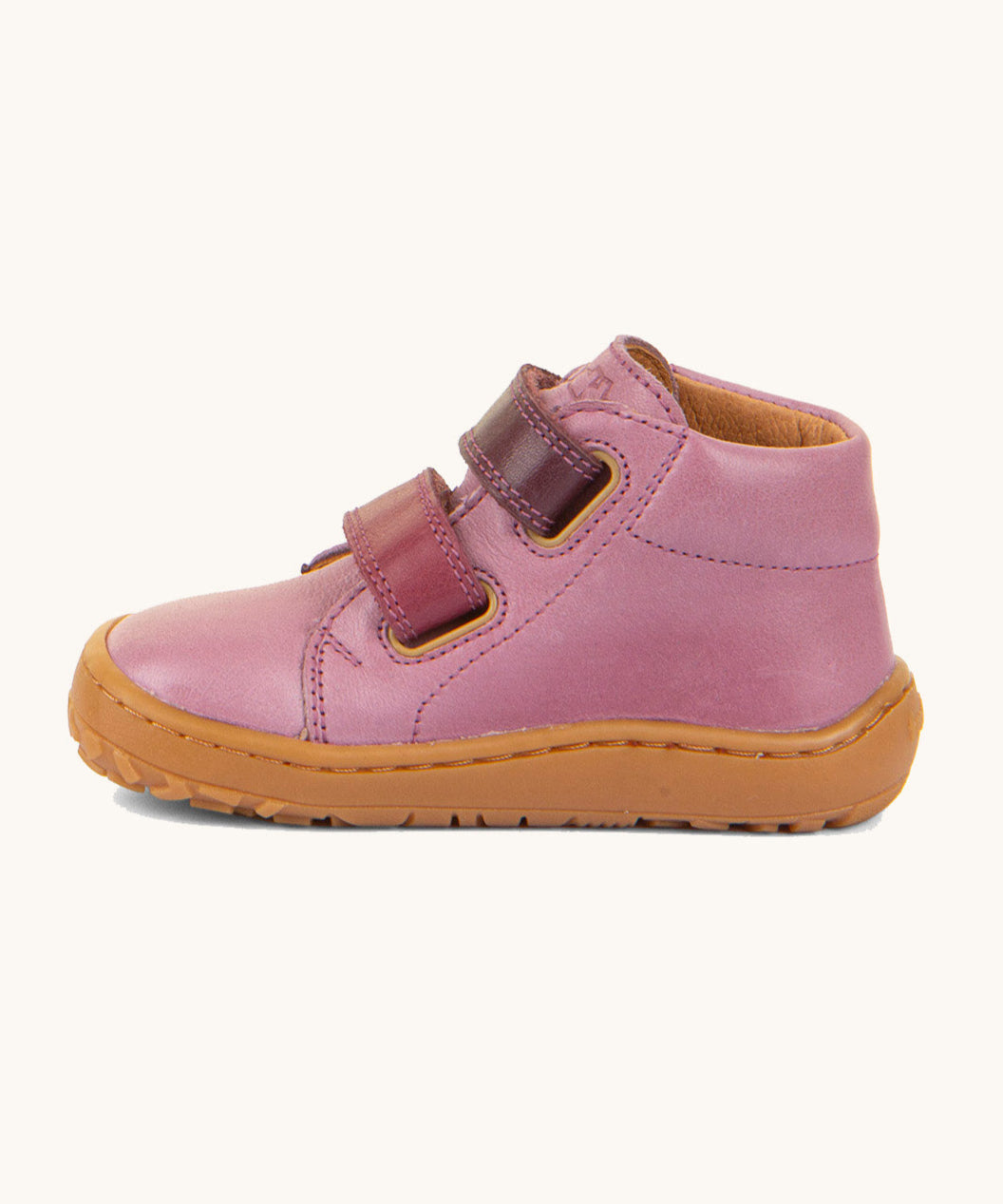 A side image of the Froddo barefoot first step baby shoe in pink available at Babipur. Showing the 2 darker pink velcro fastener for a secure fit and the light brown grippy sole