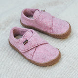 Froddo barefoot wooly children's shoe in pink standing on a pastel coloured blanket. A natural wooly shoe with a velcro fastener for a secure fit and a dark brown grippy and available at Babipur